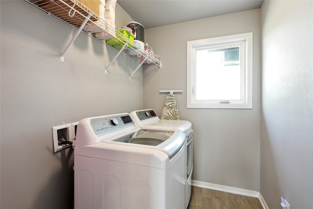 clothes washing area with hardwood / wood-style floors and washer and dryer