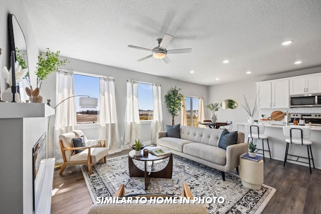 living room with ceiling fan, dark hardwood / wood-style flooring, plenty of natural light, and a textured ceiling