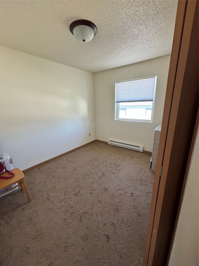 spare room with a textured ceiling, carpet flooring, and a baseboard heating unit