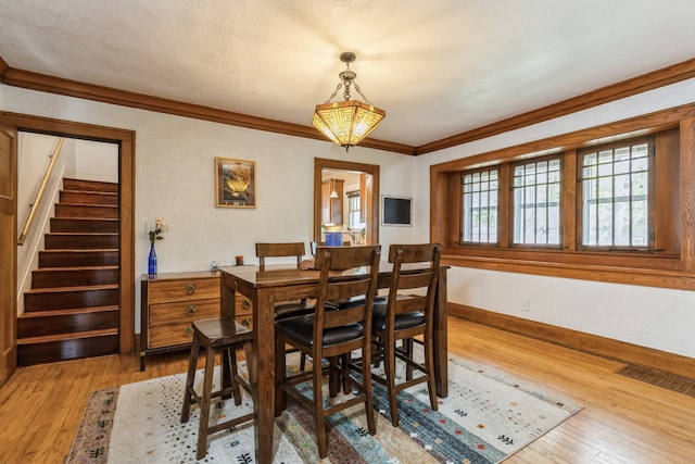 dining room with hardwood / wood-style flooring, ornamental molding, and a textured ceiling