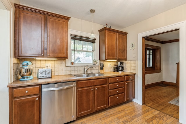 kitchen featuring light hardwood / wood-style floors, tasteful backsplash, decorative light fixtures, stainless steel dishwasher, and sink