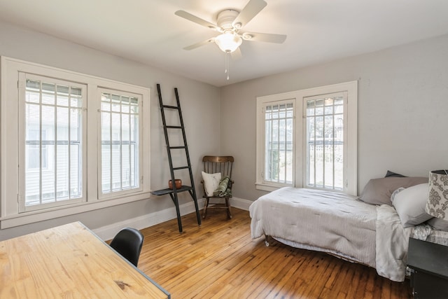 bedroom featuring ceiling fan, hardwood / wood-style floors, and multiple windows