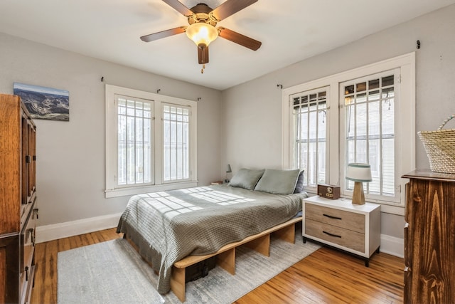 bedroom featuring ceiling fan, light hardwood / wood-style flooring, and multiple windows