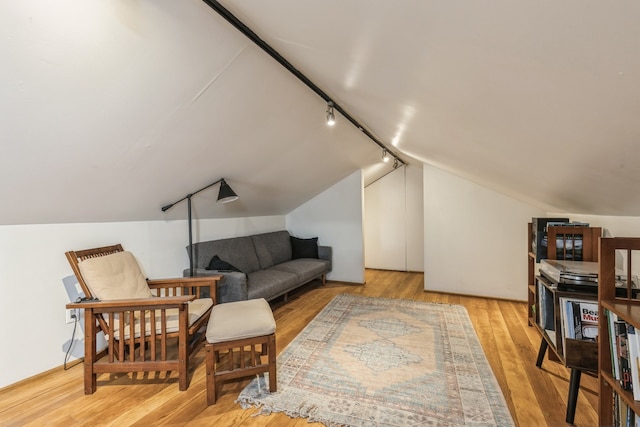 living area with light wood-type flooring, vaulted ceiling, and track lighting