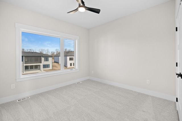 carpeted spare room featuring visible vents, ceiling fan, and baseboards