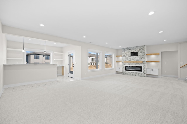 unfurnished living room featuring recessed lighting, a tiled fireplace, and light colored carpet