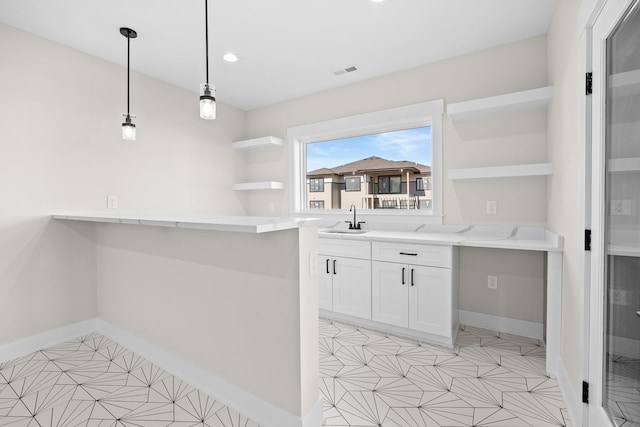 bar featuring baseboards, visible vents, a sink, and decorative light fixtures