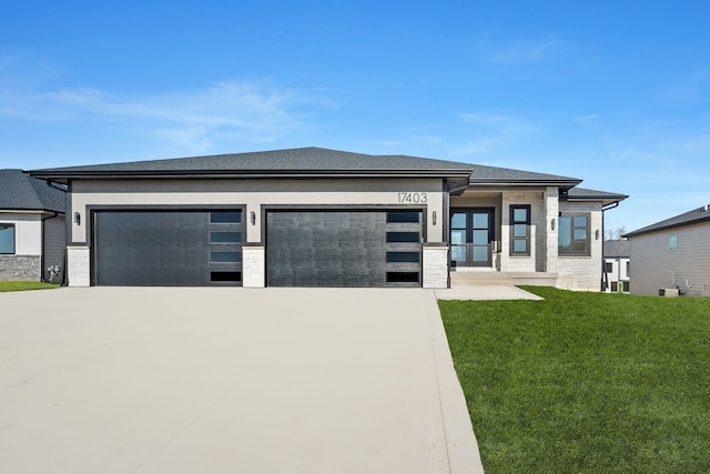 prairie-style home featuring a garage, a front lawn, and concrete driveway