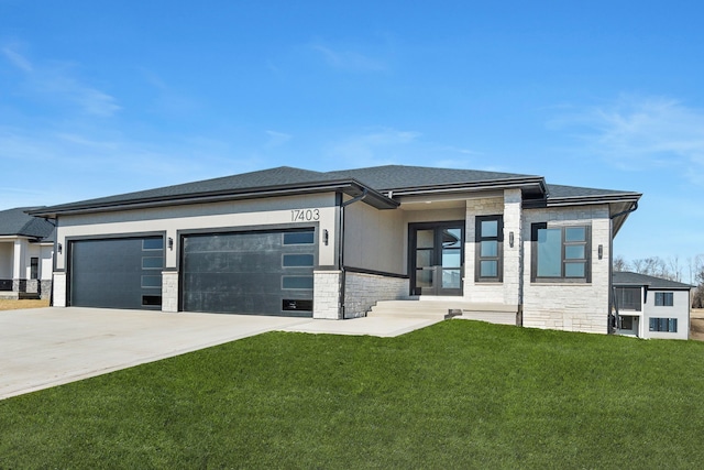 prairie-style home with stone siding, a front yard, concrete driveway, and an attached garage