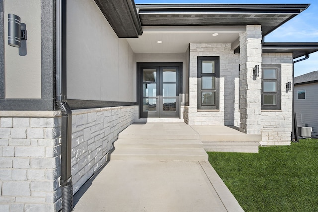 doorway to property featuring central air condition unit, stone siding, and french doors