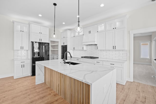 kitchen featuring black appliances, custom exhaust hood, a sink, and white cabinetry