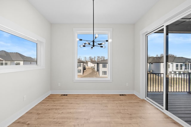 unfurnished dining area featuring plenty of natural light, wood finished floors, visible vents, and baseboards