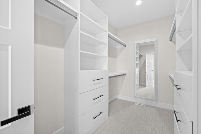 walk in closet with visible vents and light colored carpet