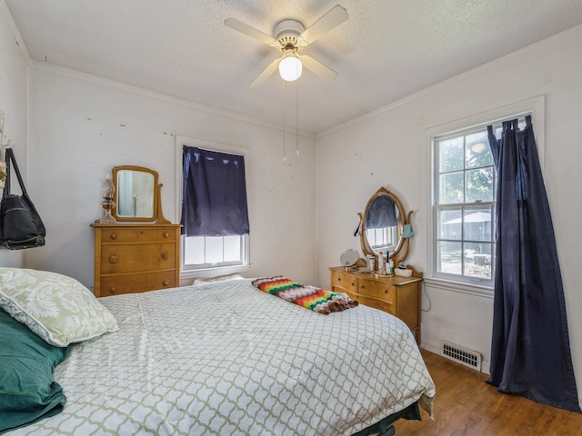 bedroom with ceiling fan, hardwood / wood-style flooring, ornamental molding, and a textured ceiling