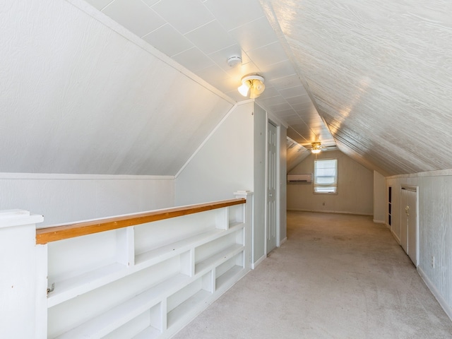 additional living space featuring vaulted ceiling, a wall mounted AC, and light carpet