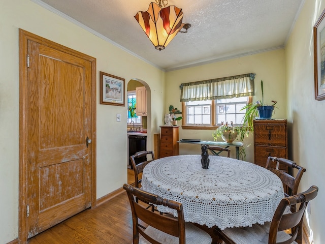 dining space featuring light hardwood / wood-style flooring, a textured ceiling, ornamental molding, and sink