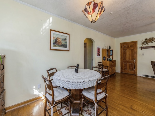 dining space featuring a textured ceiling, ornamental molding, and dark hardwood / wood-style floors