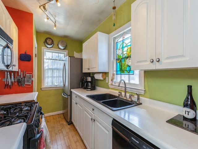 kitchen with light wood-type flooring, white cabinetry, a healthy amount of sunlight, and black appliances