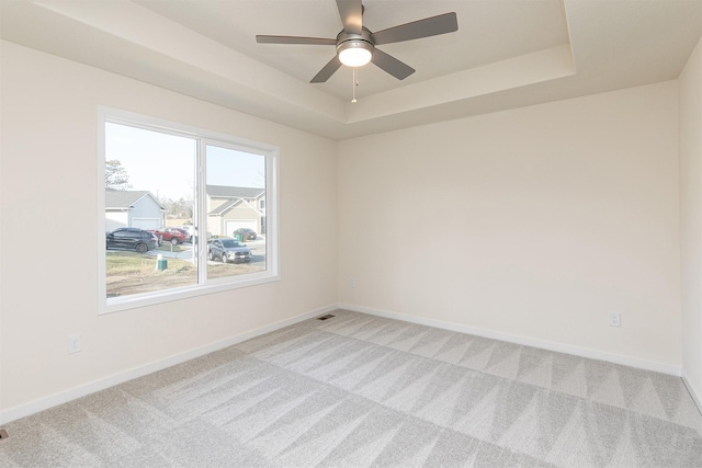 carpeted empty room featuring a tray ceiling and ceiling fan