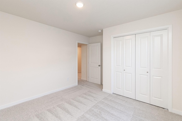 unfurnished bedroom featuring light carpet and a closet