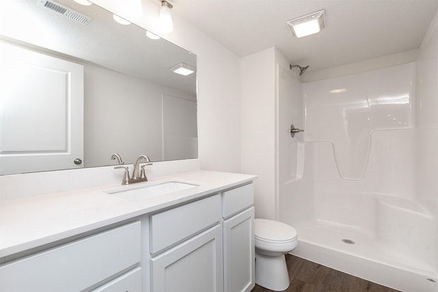 bathroom with walk in shower, toilet, vanity, and hardwood / wood-style flooring