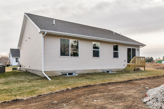 rear view of house with central air condition unit and a yard