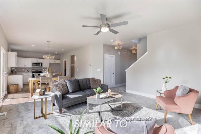 living room featuring ceiling fan, sink, and light colored carpet