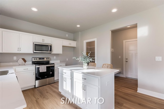 kitchen with a center island, light wood-type flooring, white cabinetry, and appliances with stainless steel finishes