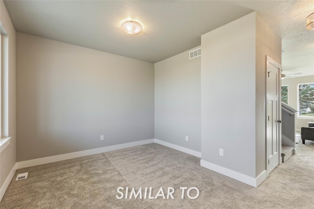 carpeted spare room with ceiling fan and a textured ceiling