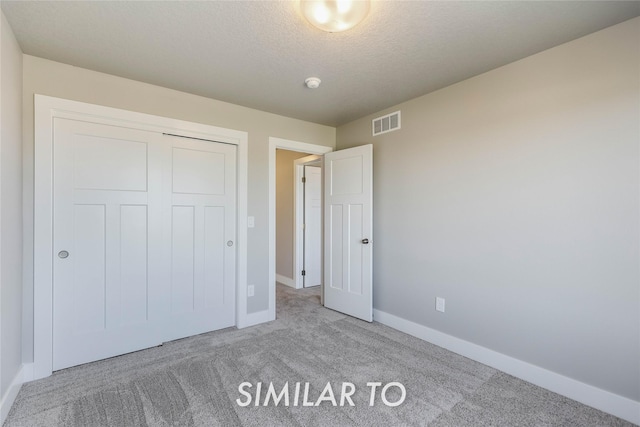 unfurnished bedroom with carpet, a textured ceiling, and a closet