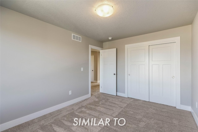 unfurnished bedroom with a textured ceiling, light colored carpet, and a closet