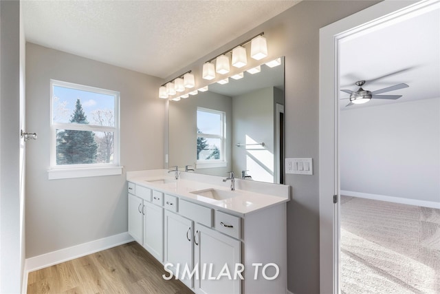 bathroom featuring hardwood / wood-style floors, vanity, ceiling fan, and a textured ceiling