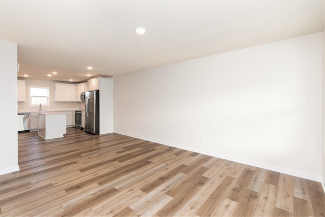 unfurnished living room featuring sink and light hardwood / wood-style flooring