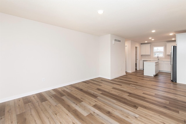 unfurnished living room featuring sink and light hardwood / wood-style floors