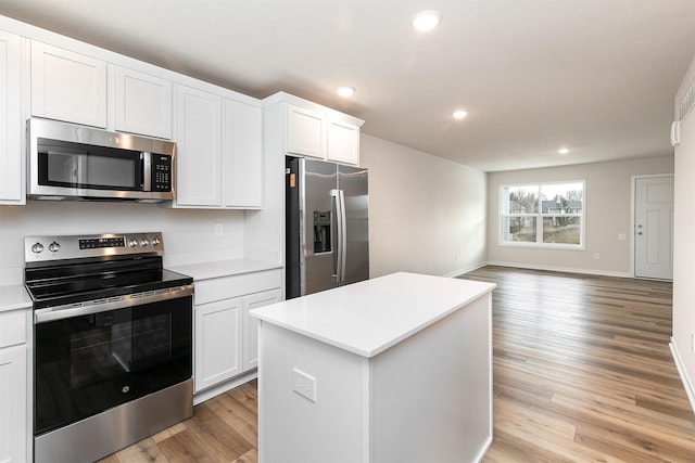 kitchen with white cabinets, a kitchen island, light wood-type flooring, and stainless steel appliances