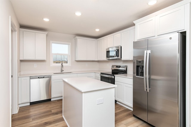 kitchen with appliances with stainless steel finishes, a center island, white cabinetry, and sink