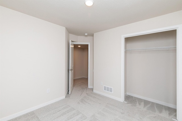 unfurnished bedroom with light carpet and a closet