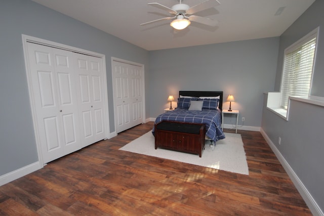 bedroom featuring multiple closets, ceiling fan, and dark hardwood / wood-style flooring