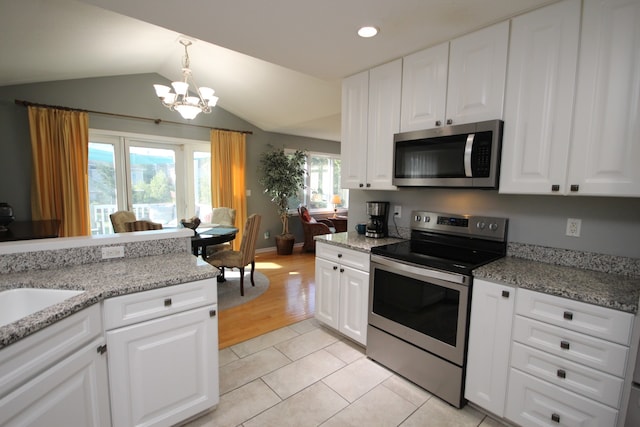 kitchen with appliances with stainless steel finishes, light wood-type flooring, vaulted ceiling, and white cabinets