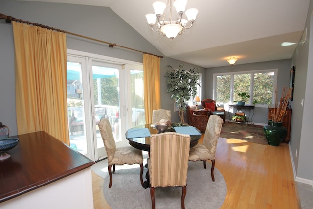 dining area with an inviting chandelier, lofted ceiling, light hardwood / wood-style floors, and a healthy amount of sunlight