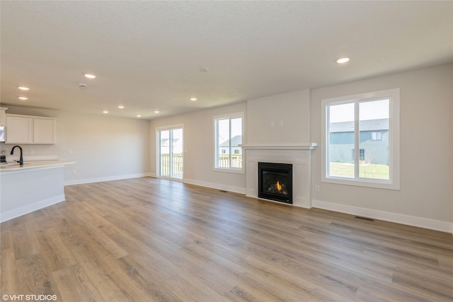 unfurnished living room featuring sink and light wood-type flooring