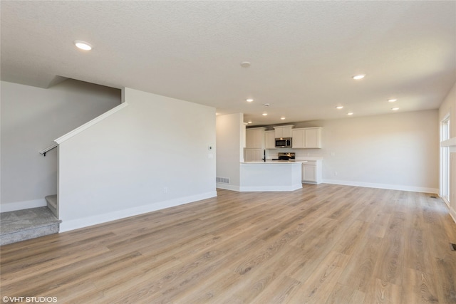 unfurnished living room featuring a textured ceiling and light hardwood / wood-style flooring