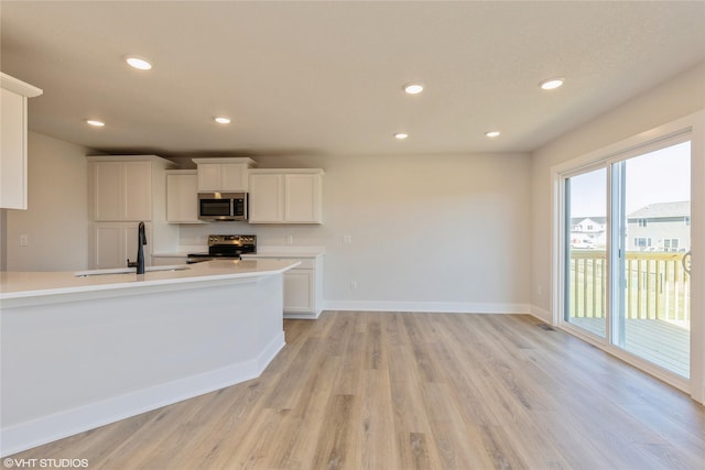 kitchen featuring white cabinets, stainless steel appliances, light hardwood / wood-style flooring, and sink