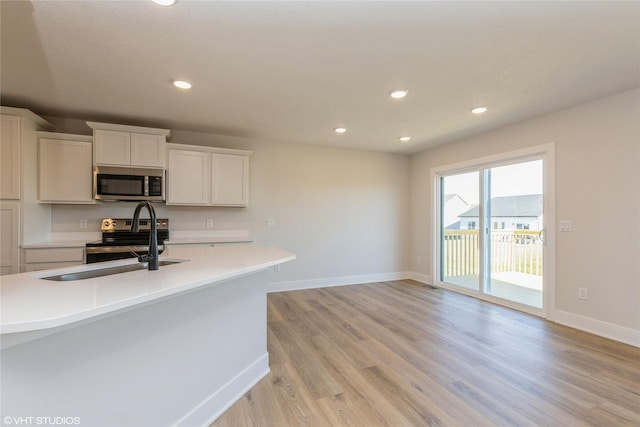 kitchen with sink, white cabinetry, light hardwood / wood-style flooring, and appliances with stainless steel finishes