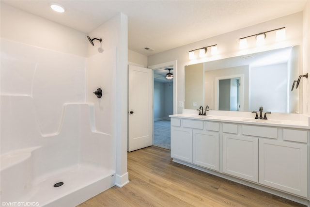 bathroom featuring ceiling fan, hardwood / wood-style floors, walk in shower, and vanity