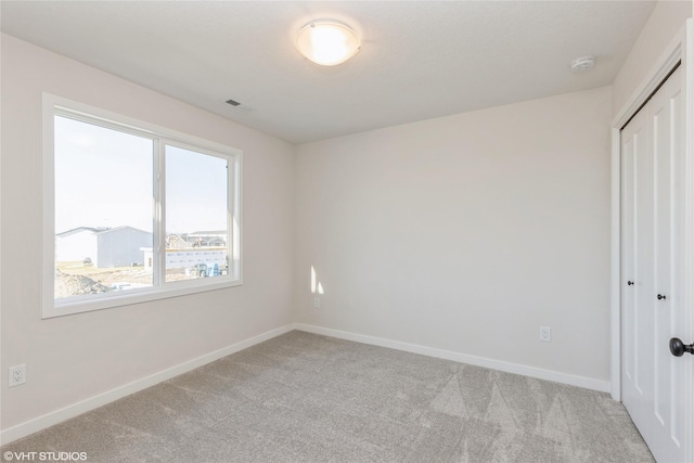 unfurnished bedroom with light colored carpet and a closet