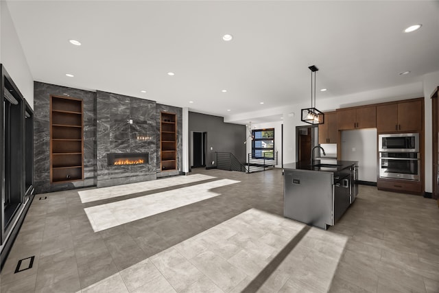 kitchen with pendant lighting, sink, a fireplace, appliances with stainless steel finishes, and dark brown cabinetry