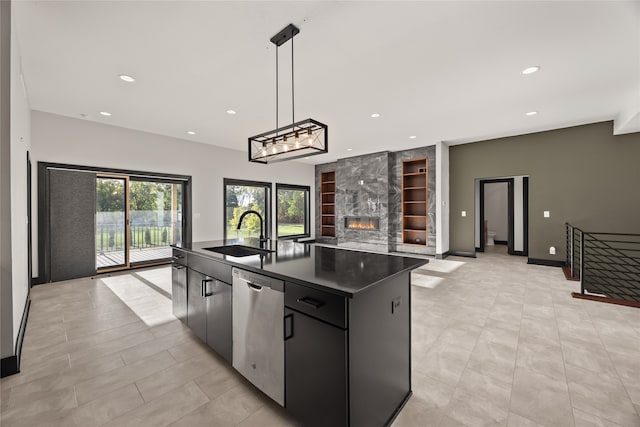 kitchen featuring a kitchen island with sink, sink, hanging light fixtures, a large fireplace, and stainless steel dishwasher