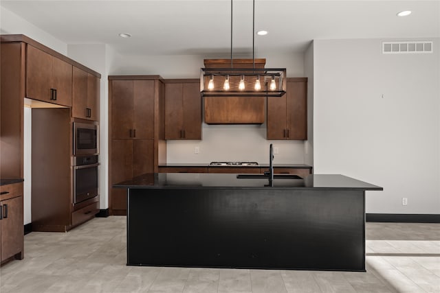 kitchen featuring appliances with stainless steel finishes, a kitchen island with sink, sink, and decorative light fixtures