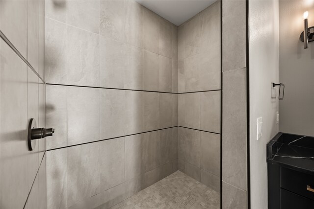 bathroom with a tile shower and vanity